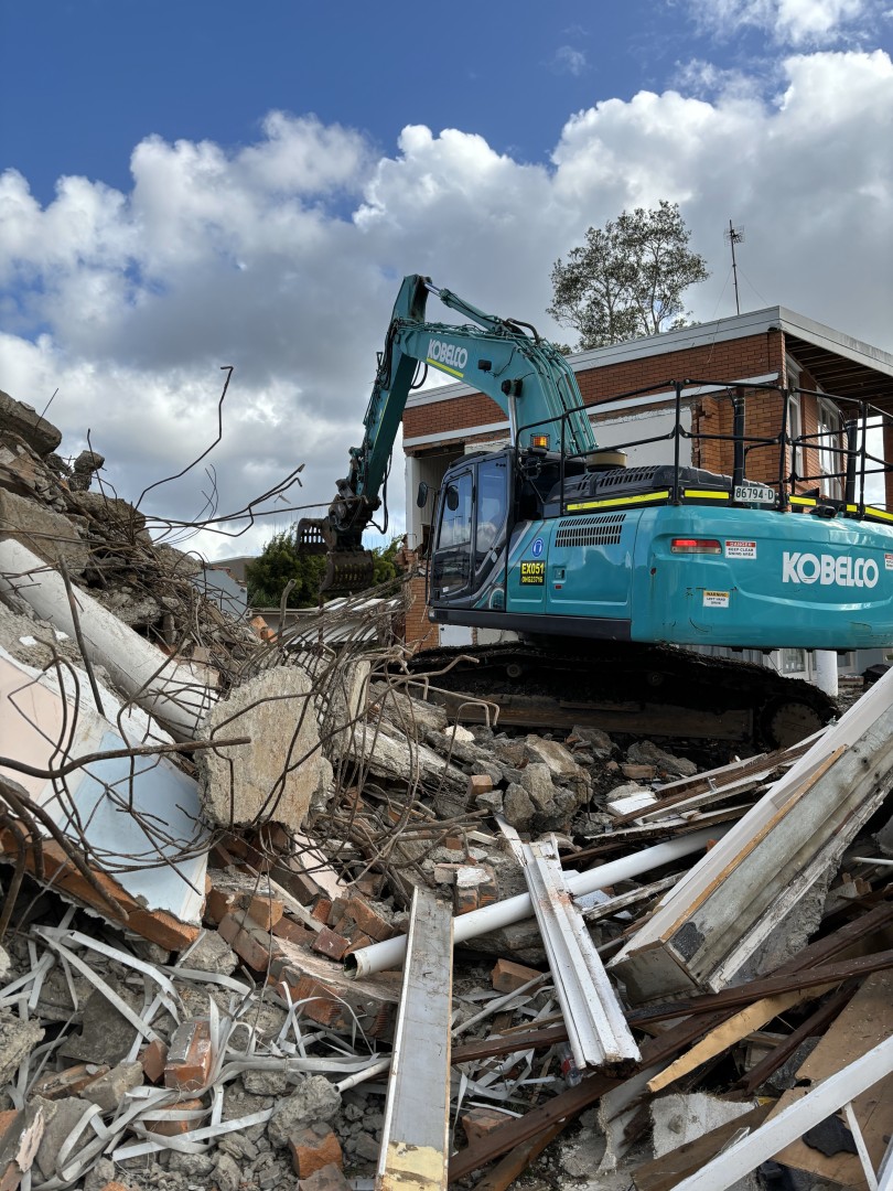 Yellow CAT heavy demolition machine demolishing a residential house near the river