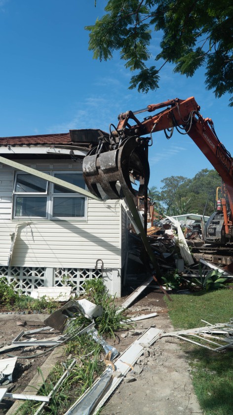 Residential house being demolished by an excavator during a demolition service brisbane